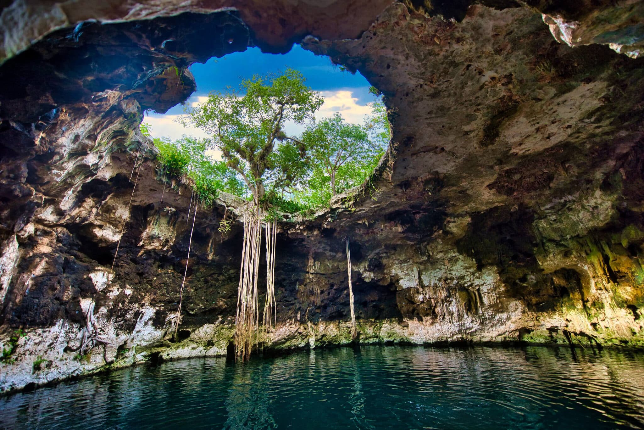 Sunlight illuminating a turquoise cenote cave in Yucatán